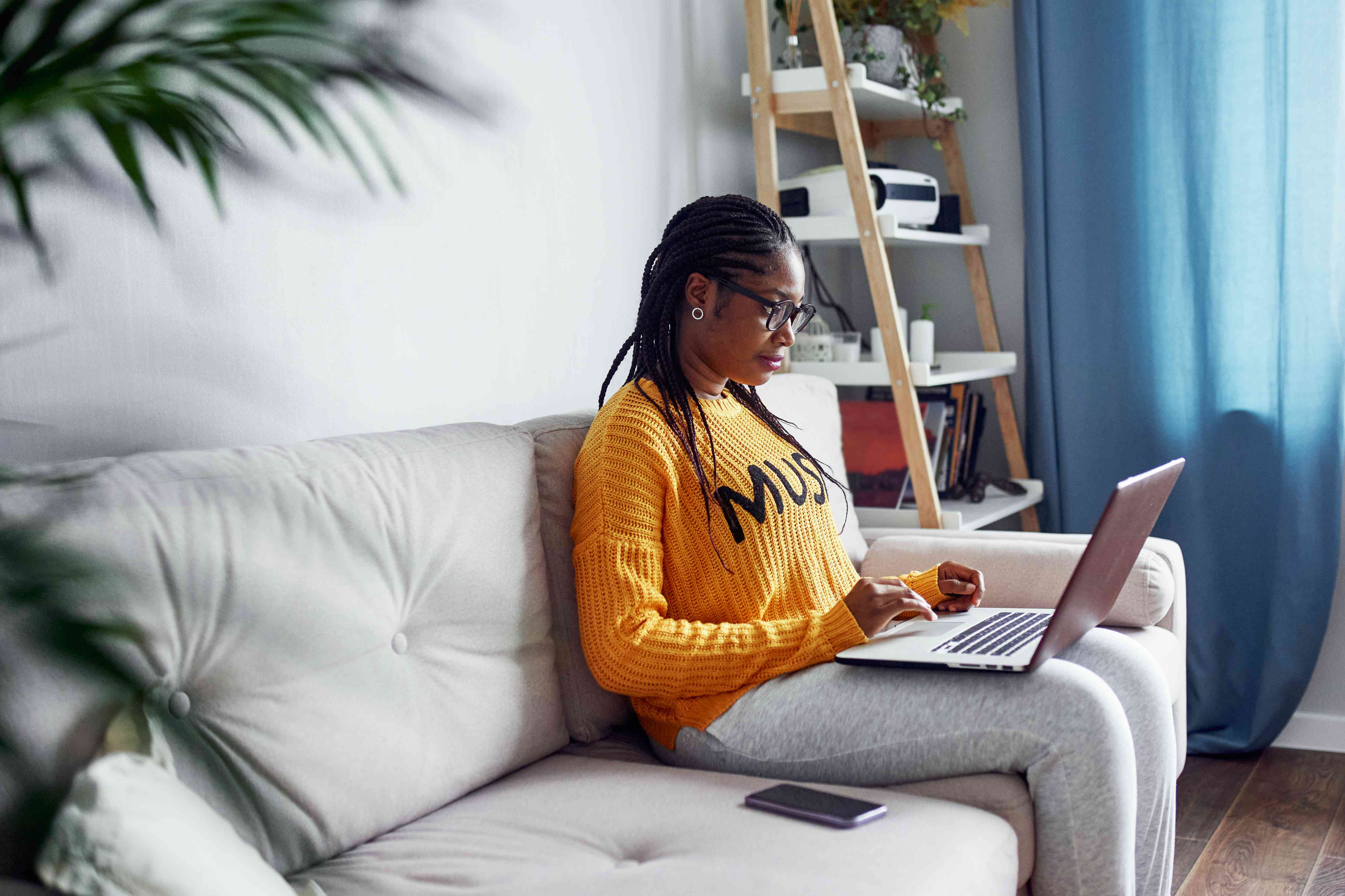 A woman sits at a computer, considering her finances.