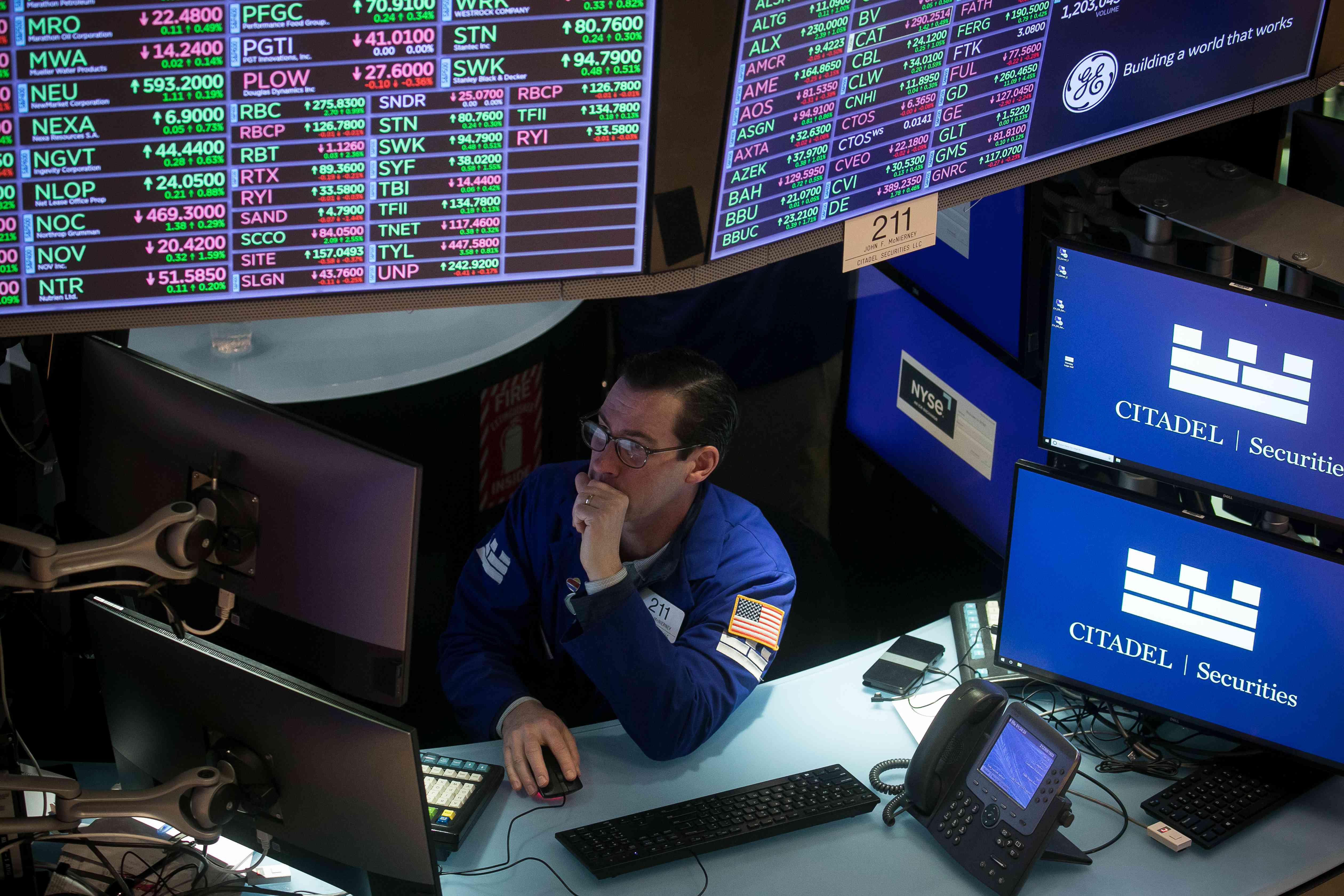 A trader looks at a screen while sitting at a desk on the floor of the New York Stock Exchange