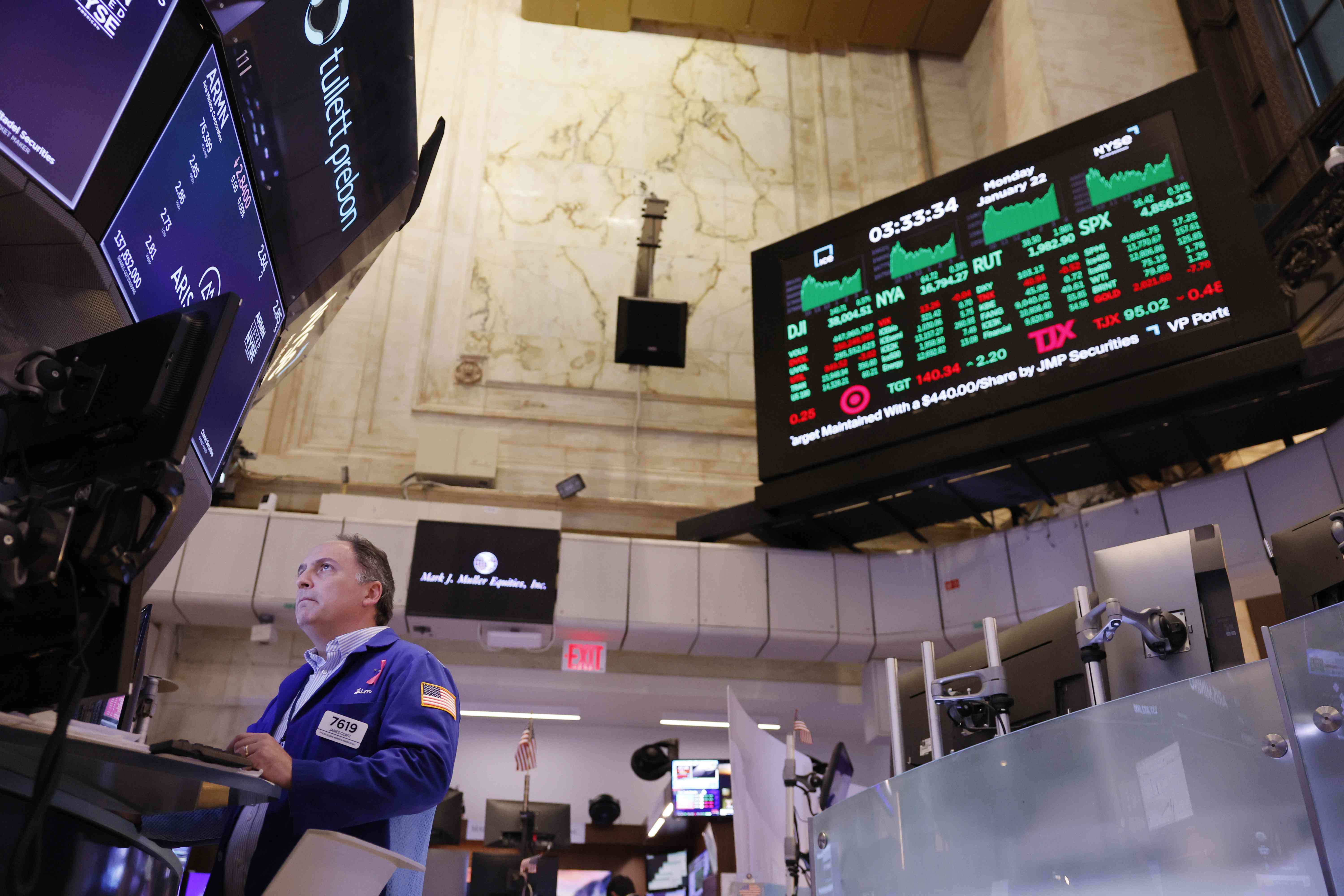 A trader looks up at computer screens on the floor of the New York Stock Exchange