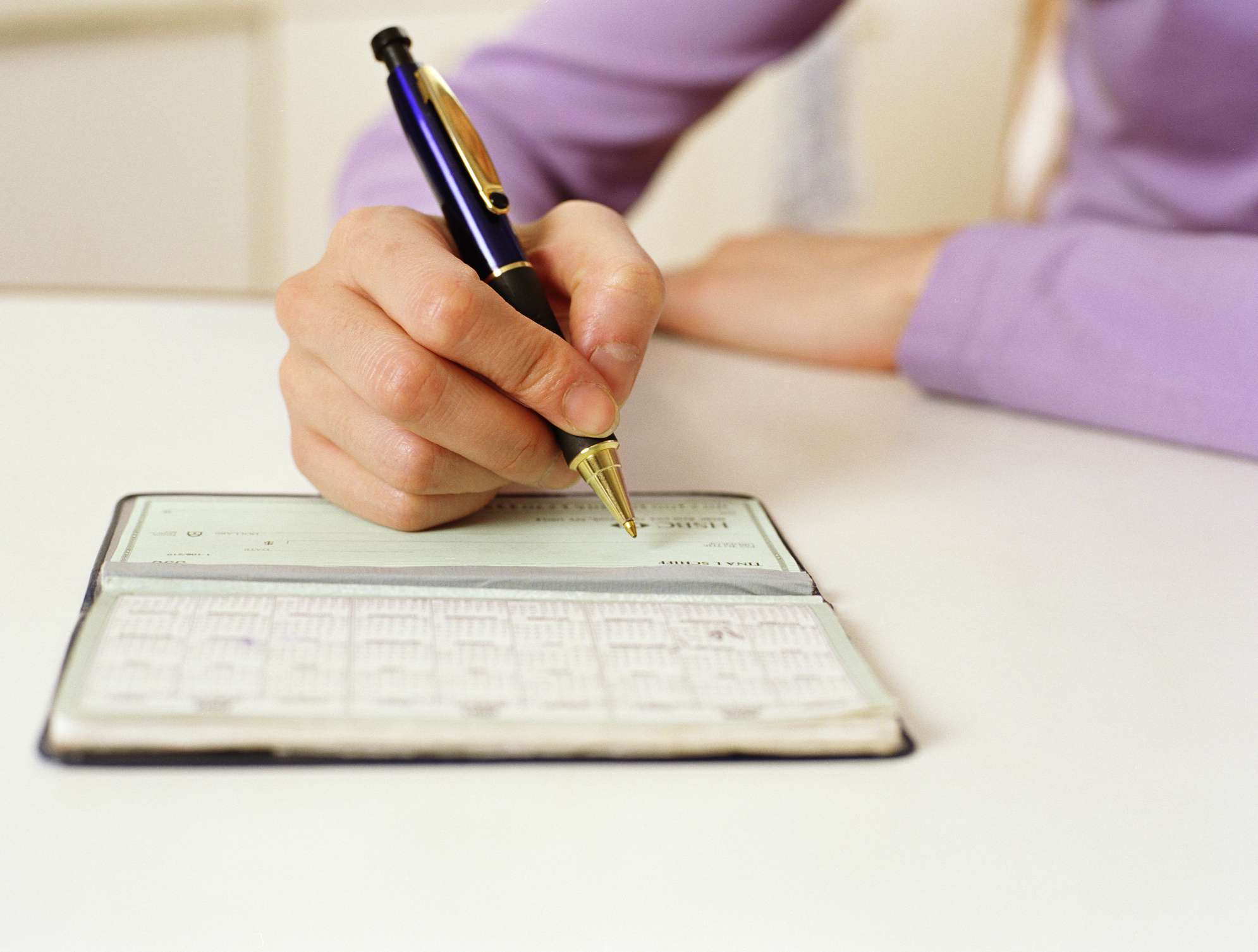 Woman writing in a check book.