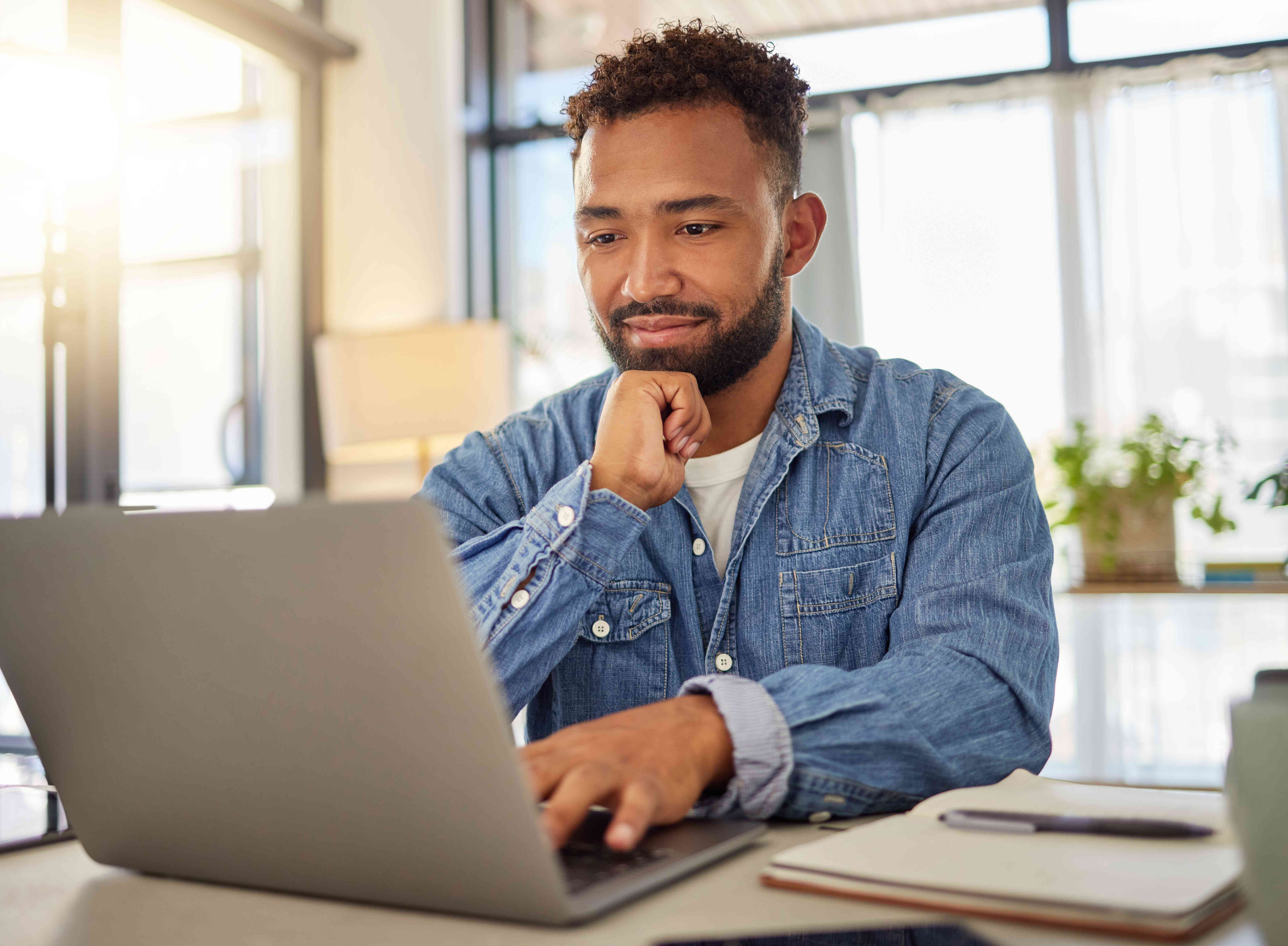 a person sitting in an office in front of a laptop looking intently at the screen 