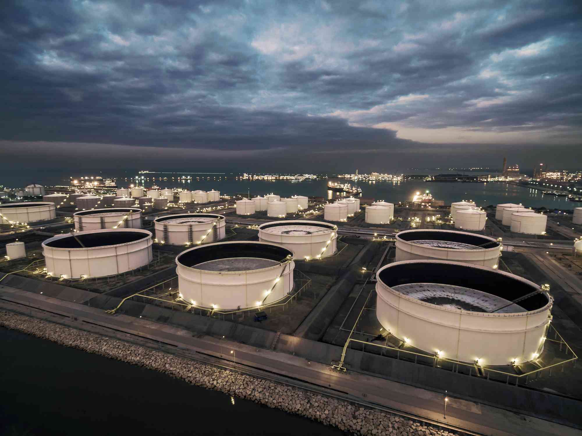 Oil storage tank in oil refinery near the sea at night, Rayong, Thailand.