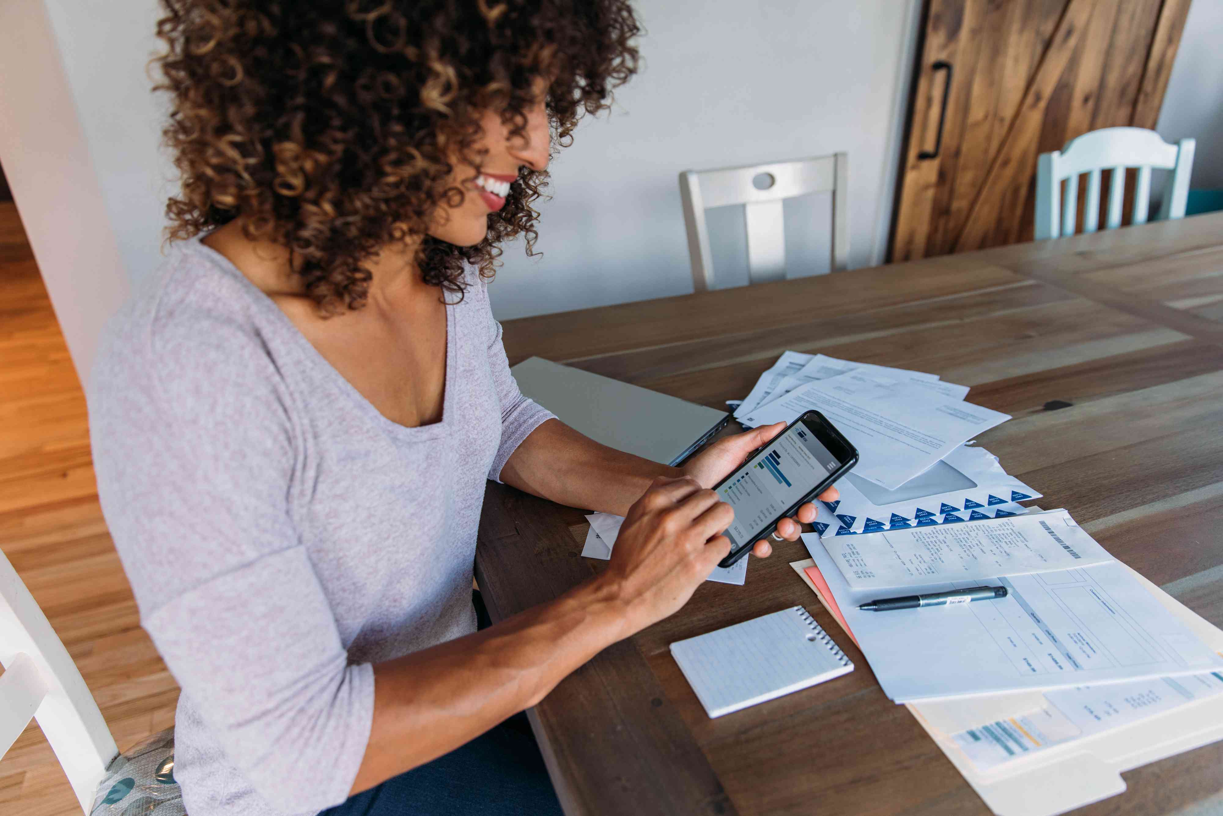 Woman working on her Finances at Home on her Smart Phone