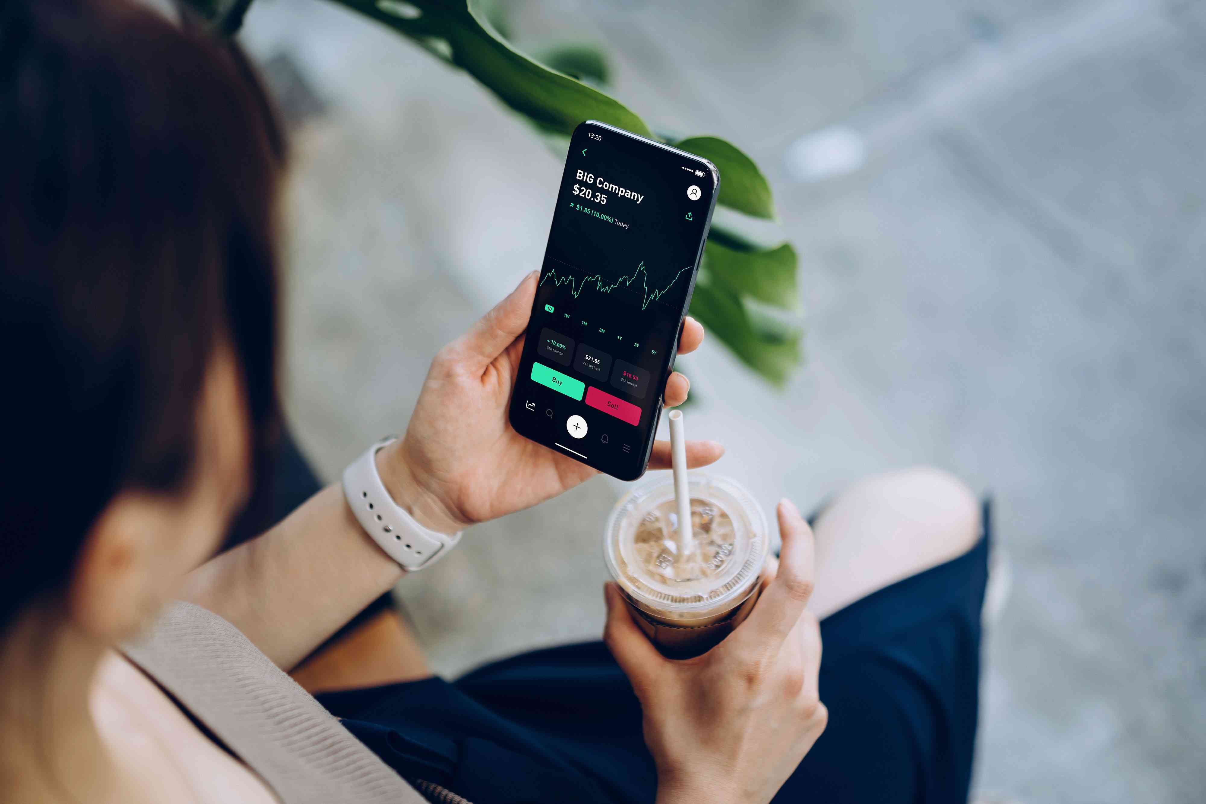 Over the shoulder view of young Asian woman checking financial trading data with mobile app