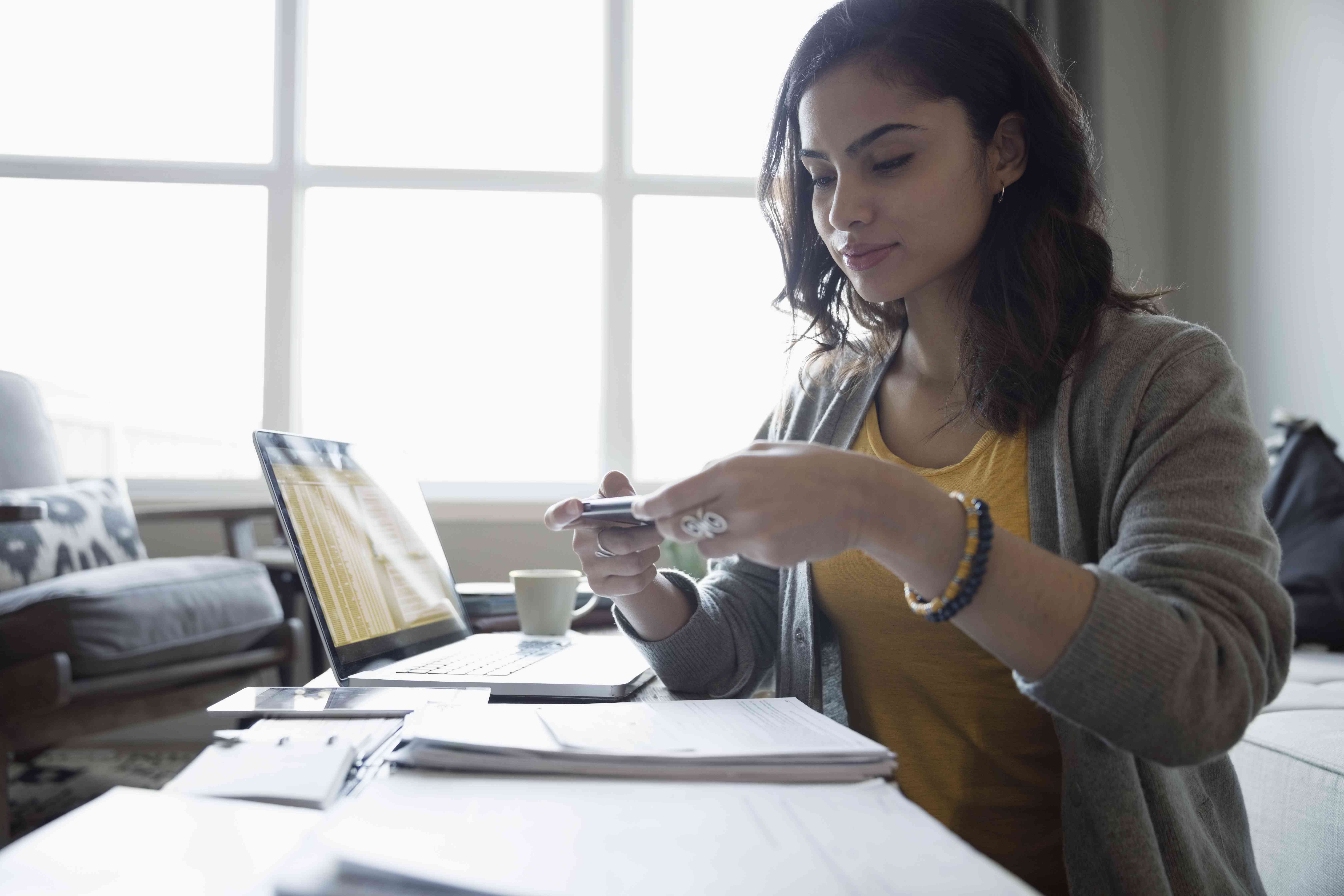 Young woman depositing check online with camera phone in living room